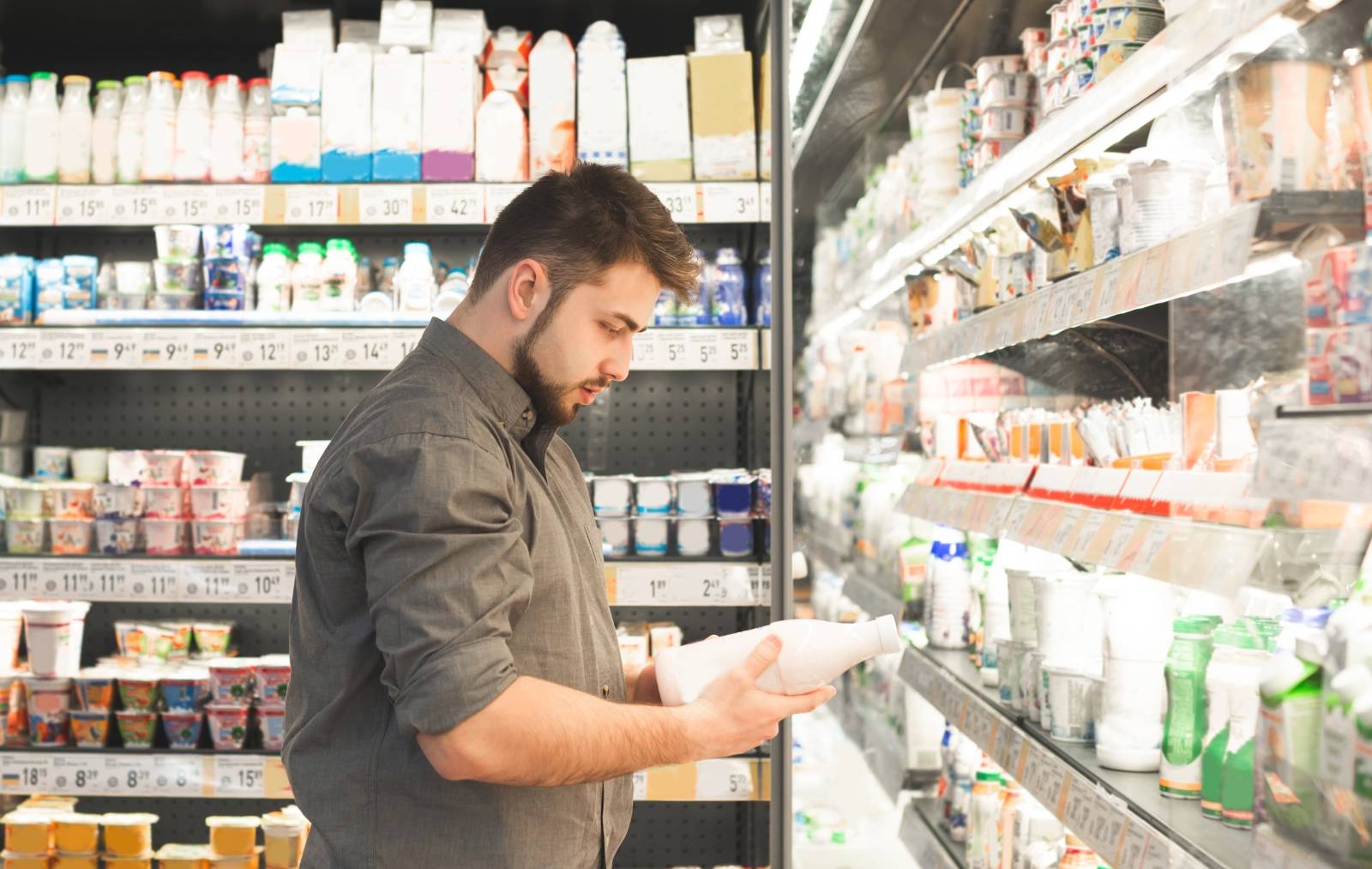 A man in a supermarket looking at the labels on groceries.