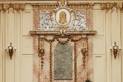 Na protější straně ochozu se nachází reliéfní dekorace v podobě symbolu spořitelny – zlatého úlu. Na mramorové desce pod ním je latinský nápis, který v překladu znamená: „Ředitelství této pokladnice, která je občanům věnovaná do užívání od roku 1825, nechalo roku 1896 pro potřeby veřejnosti vystavět tuto prostornou dvoranu.“